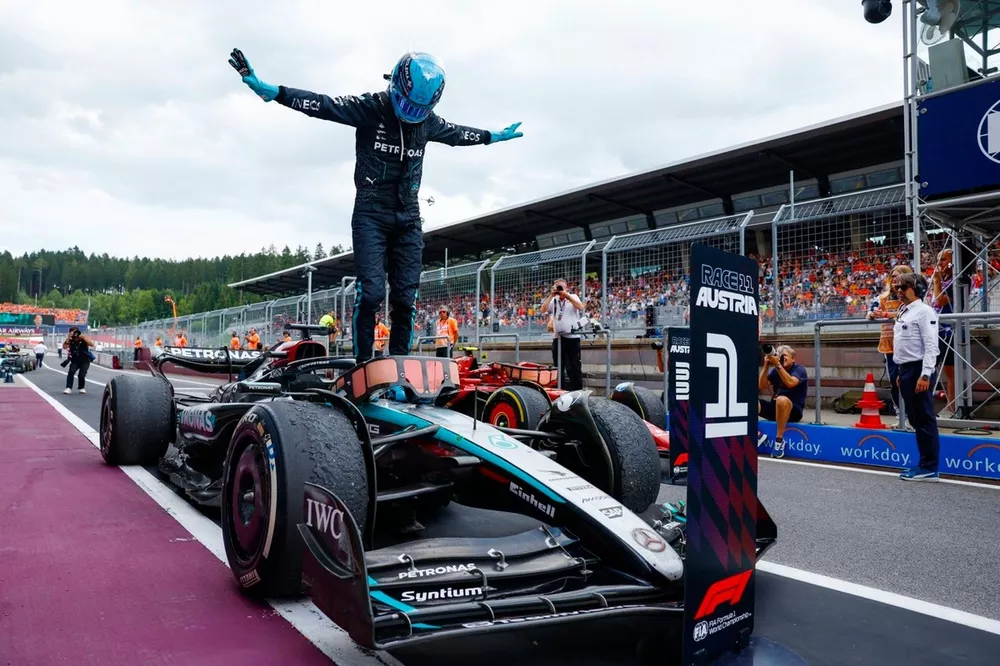 George Russell striking his trademark T-pose on top of his car after a race