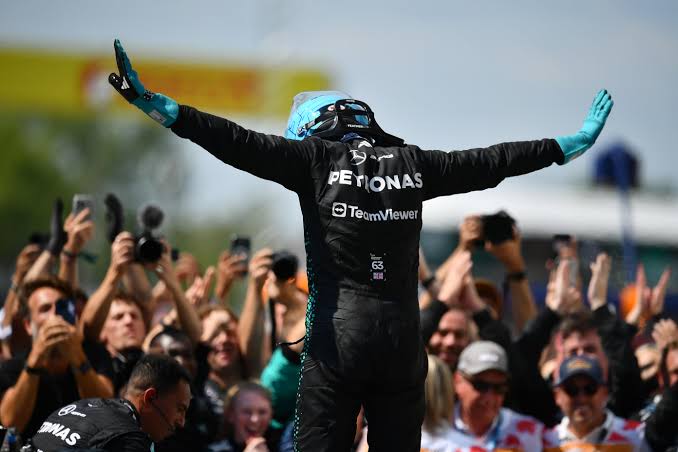 George Russell facing the crowd with arms outstretched in the T-pose